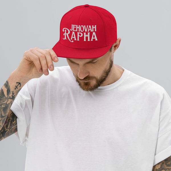 Man wearing red Jehovah Rapha flat bill trucker hat angled view