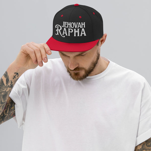 Man wearing black and red Jehovah Rapha flat bill trucker hat