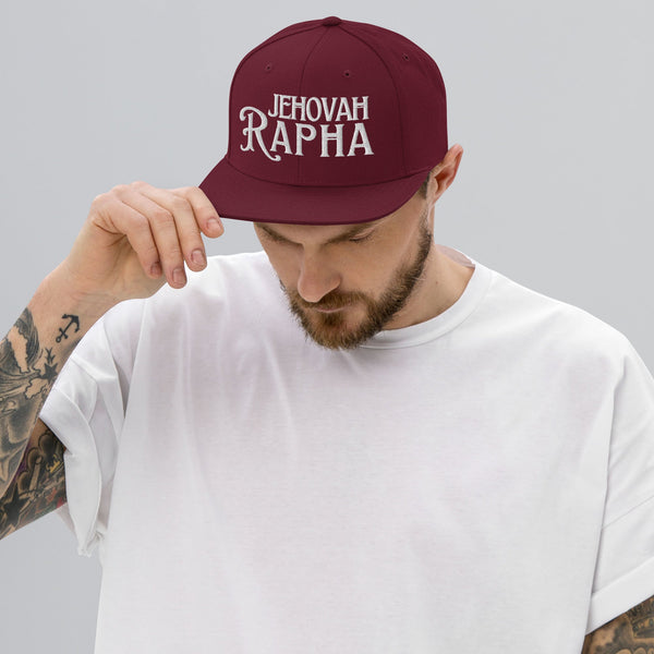 Man wearing burgundy Jehovah Rapha flat bill trucker hat
